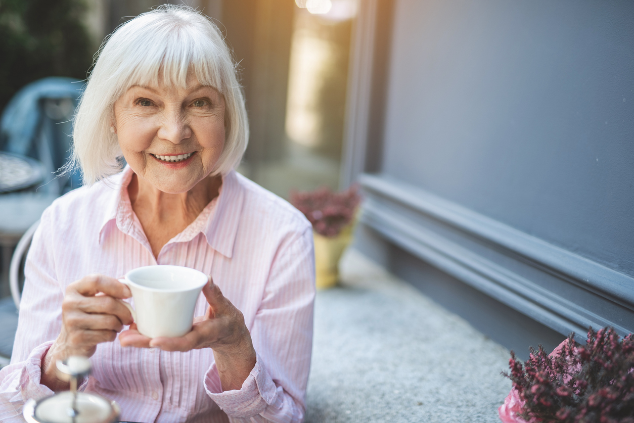 Attraktive ältere Dame hält eine Tasse Kaffee in der Hand