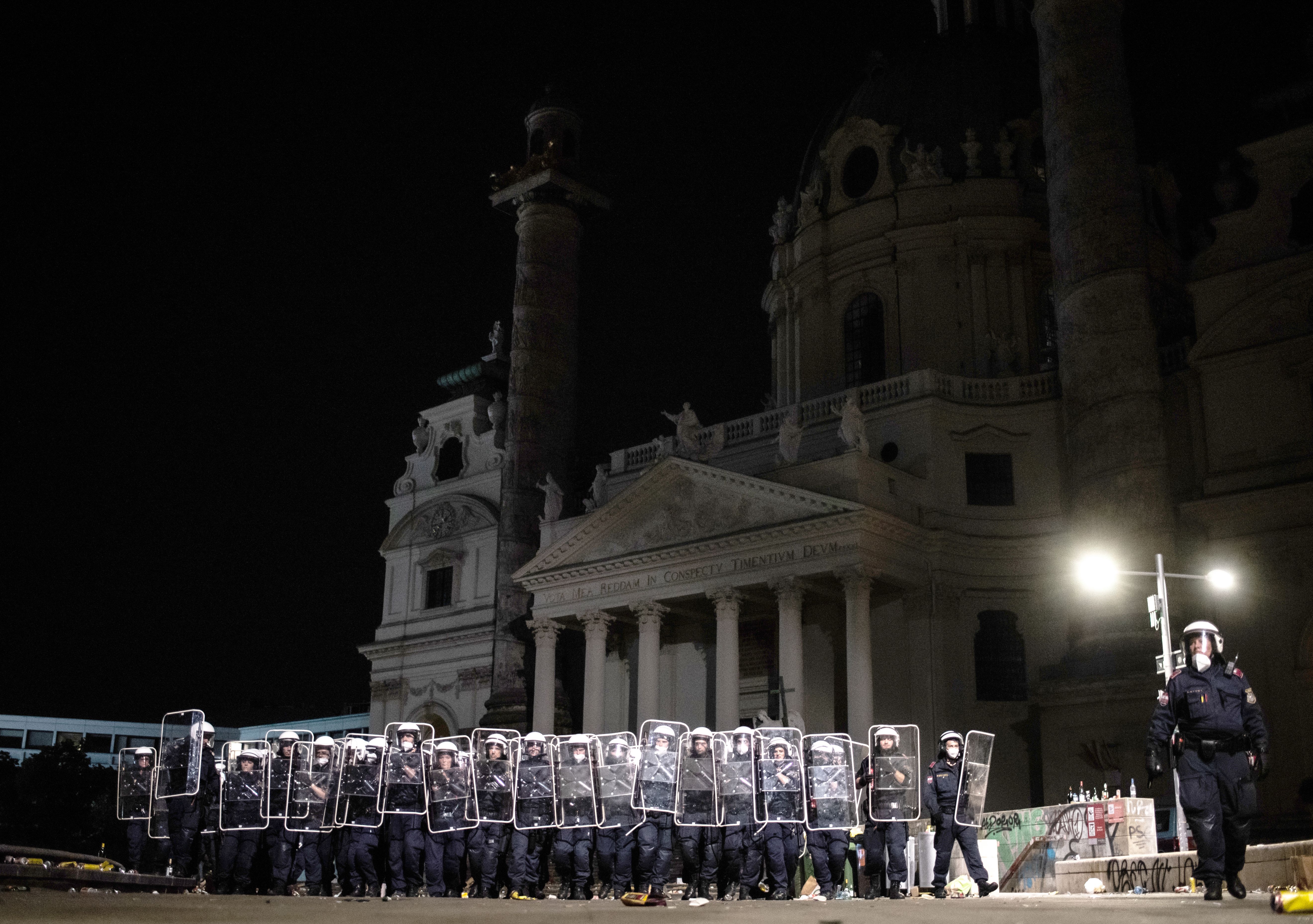 Polizisten schützen sich mit Schildern am nächtlichen Karlsplatz