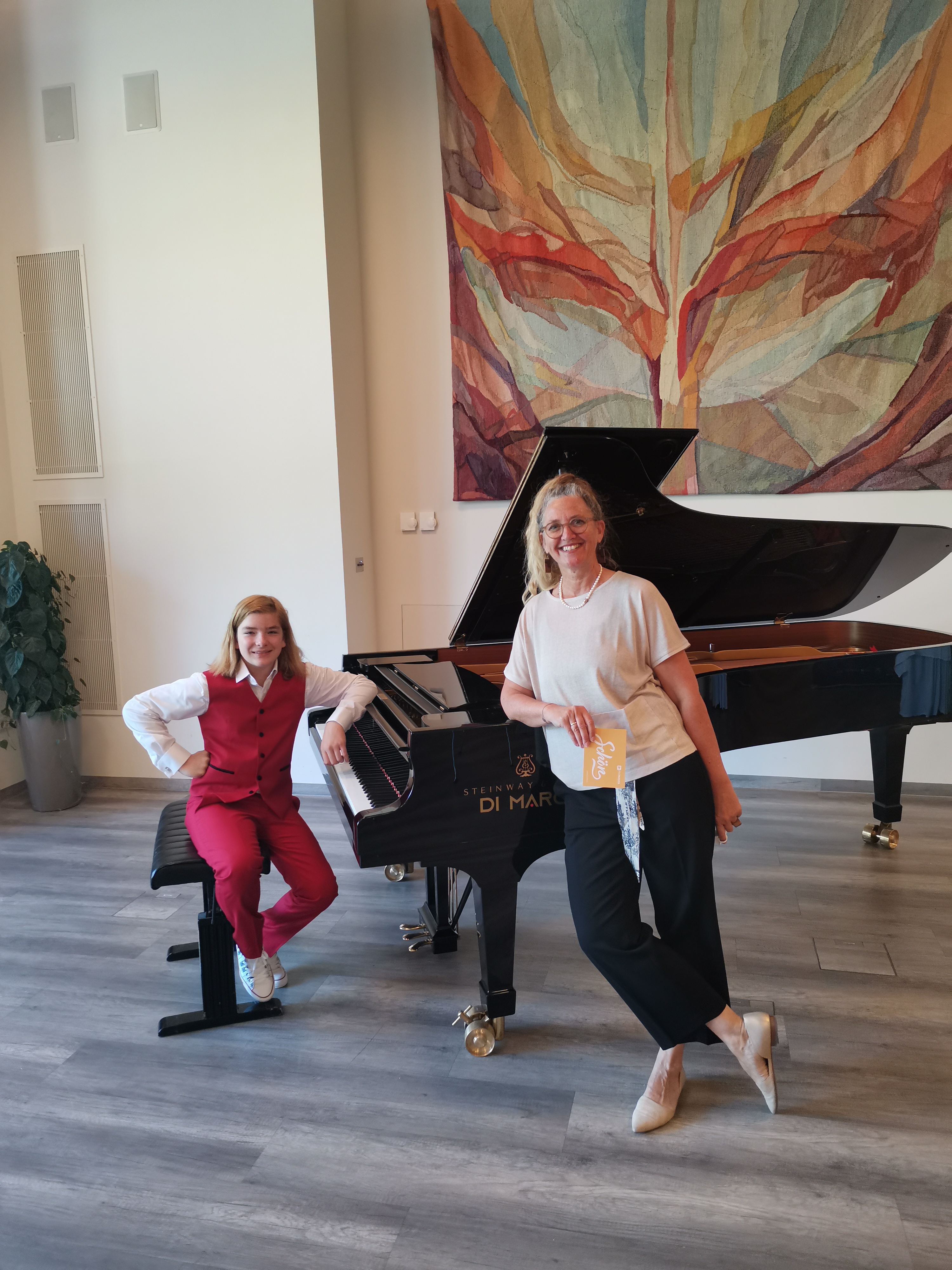 Der jugendliche Pianist Elias Keller sitzt an einem Flügel an dem die Obfrau des Musikvereins Promusica Carinthia lehnt