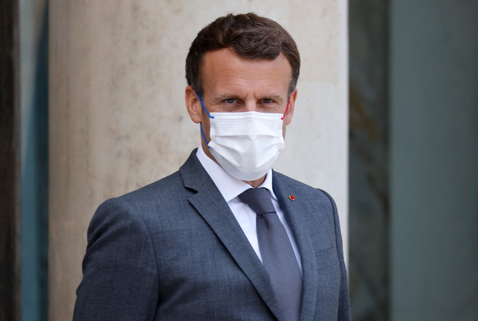 Ein Porträt-Foto von Präsident Macron: Er trägt einen grauen Anzug mit Krawatte und einen weißen Mund-Nasen-Schutz.