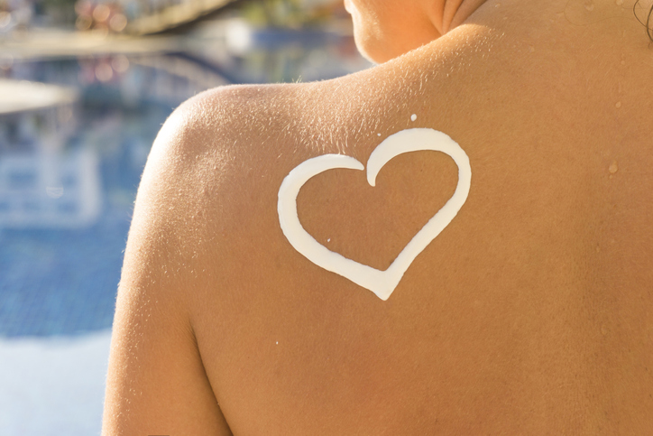 Frau mit Herz aus Sonnenmilch auf der Schulter