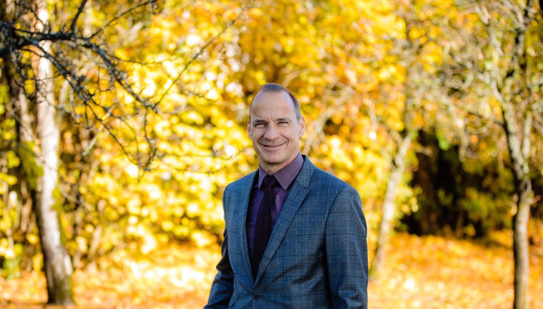 Raiffeisen-Berater Ferdinand Wallenböck steht vor einer herbstlichen Kulisse im Wald