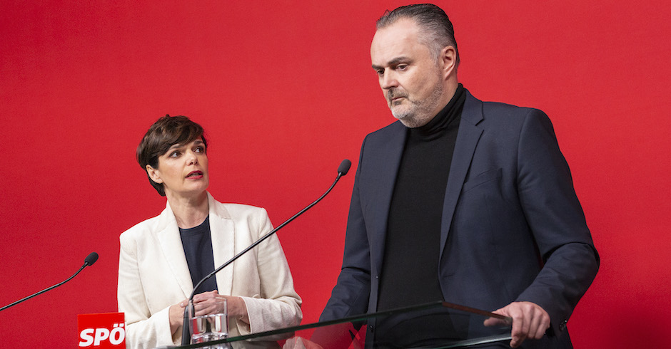Pamela Rendi-Wagner und Doskozil am Rednerpult auf einer Pressekonferenz vor rotem Hintergrund. Doskozil spricht sehr ernst, Rendi-Wagner sieht ihn skeptisch von der Seite an.