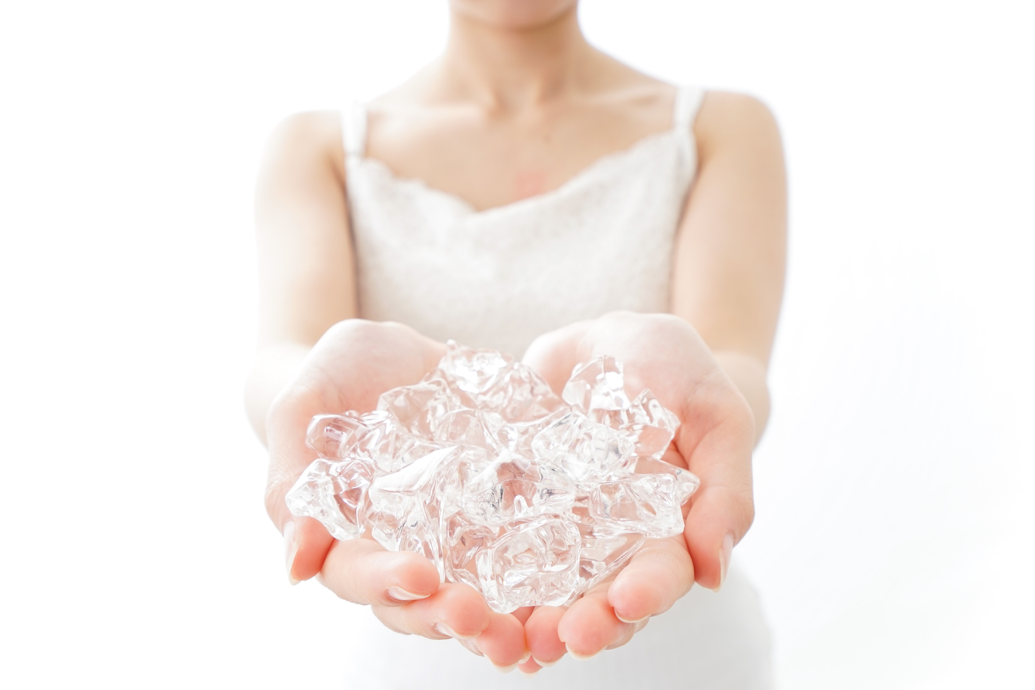 Eine Handvoll Eiswürfel in den Händen einer jungen Frau