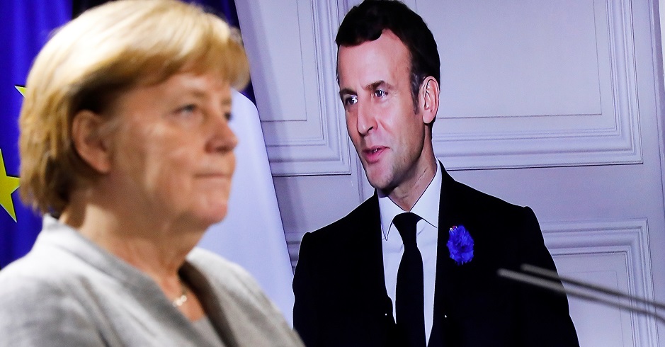 Angela Merkel im Vordergrund vor einer europäischen Fahnen. Dahinter auf einem Bildschirm Emmanuel Macron.