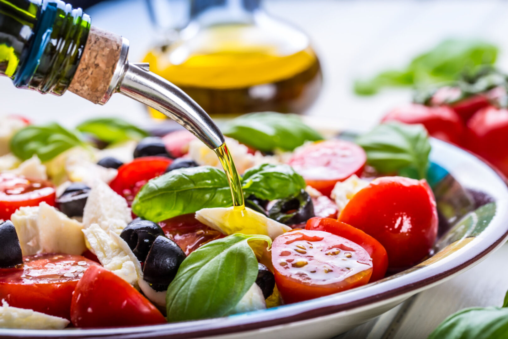 Caprese-Salat wird mit Olivenöl angerichtet | Credit: iStock.com/MarianVejcik
