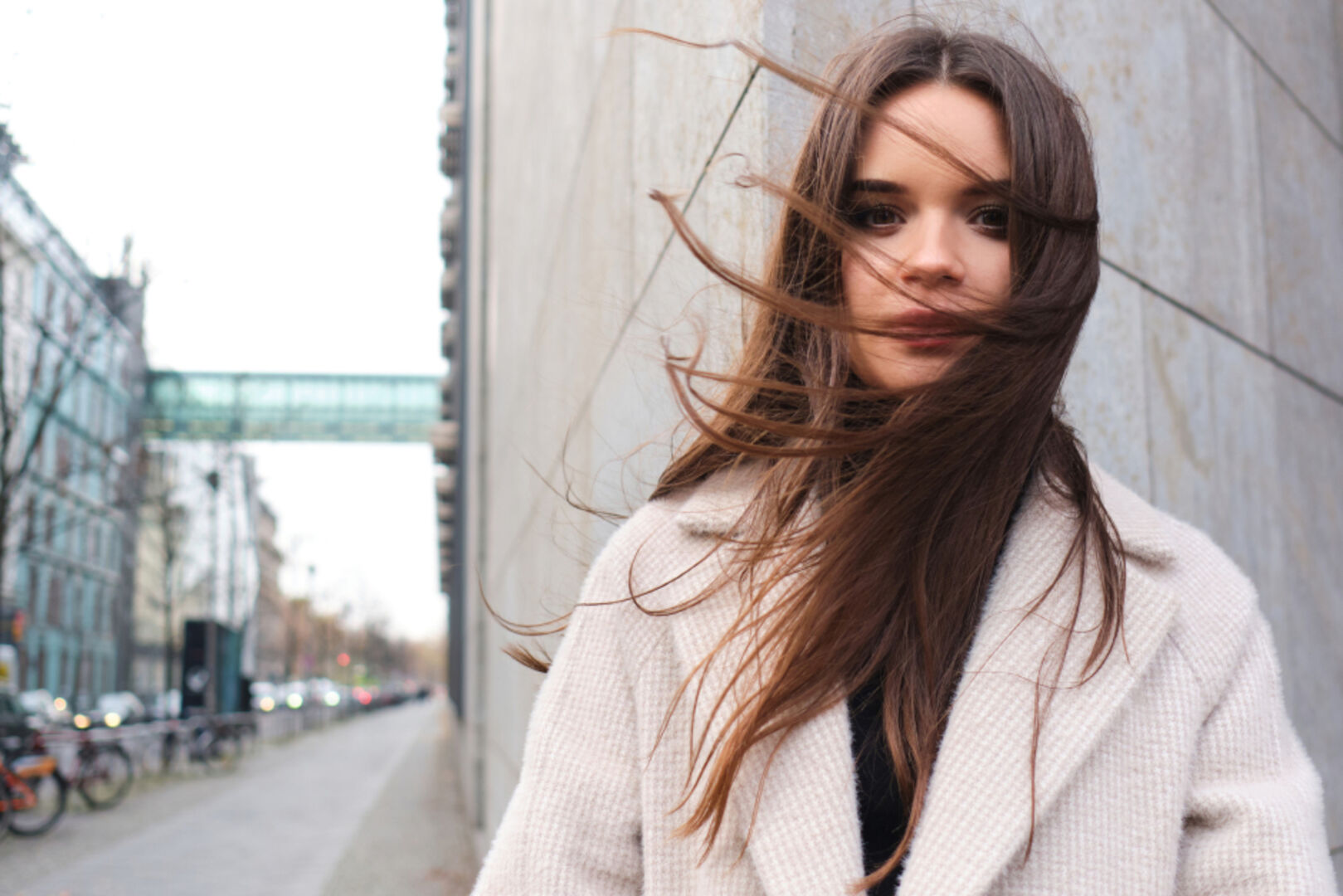 Frau mit wehenden Haaren in den Straßen einer Stadt | Credit: iStock.com/Garetsworkshop