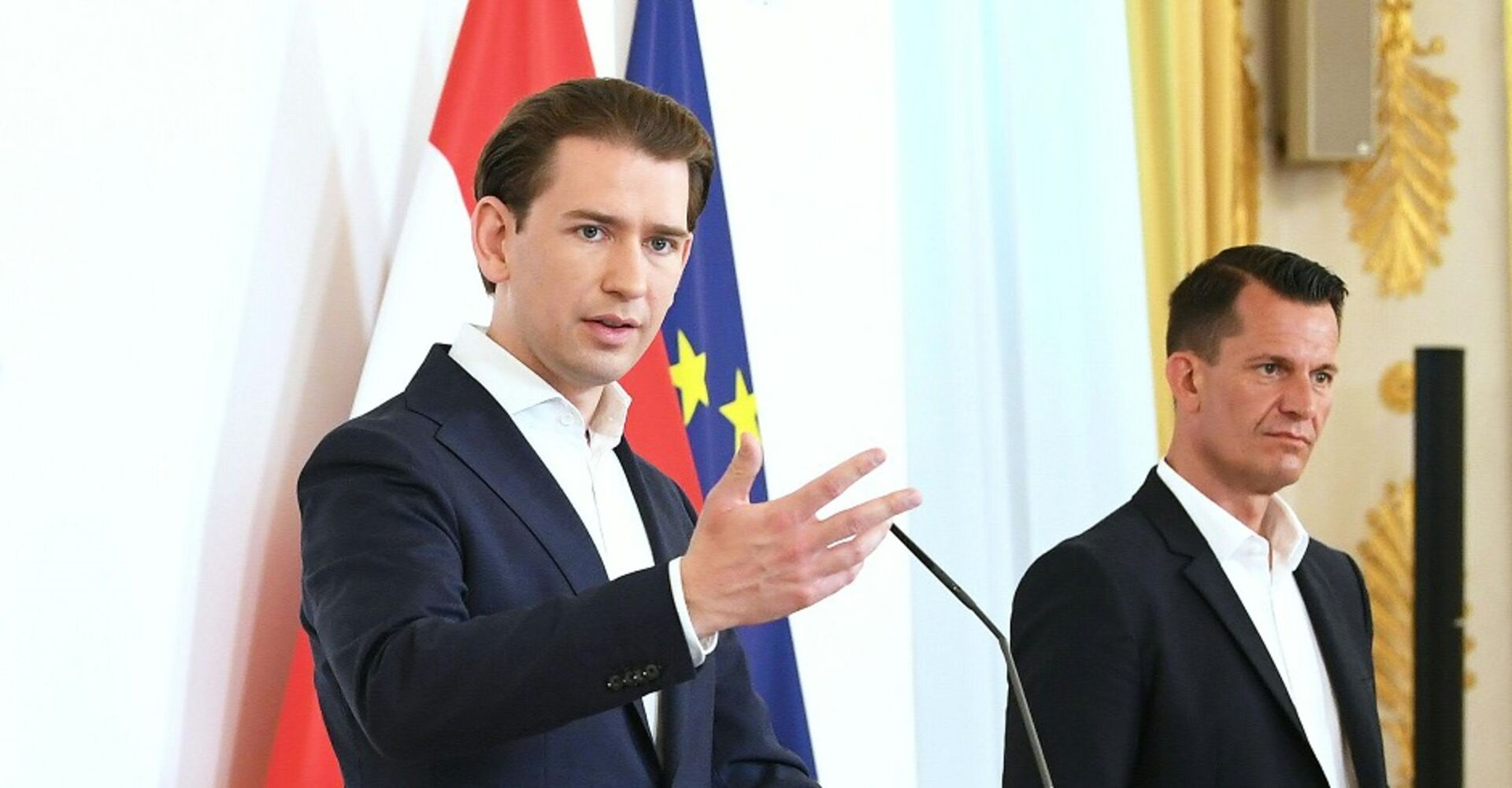 Sebastian Kurz und Wolfgang Mückstein stehen vor der Österreich- und der EU-Fahnen und geben eine Pressekonferenz. Der Kanzler spricht und gestikuliert.