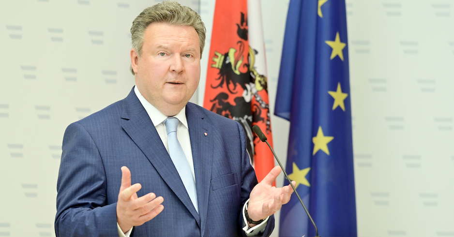 Bürgermeister Michael Ludwig steht vor einer österreichsichen und europäischen Flagge und spricht in ein Mikrofon.