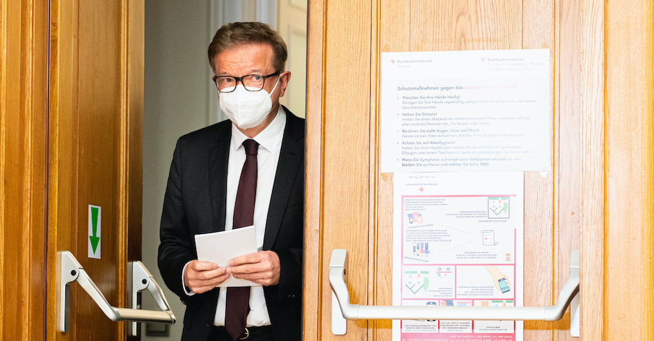 Rudolf Anschober geht im Sozialministerium durch eine große Tür