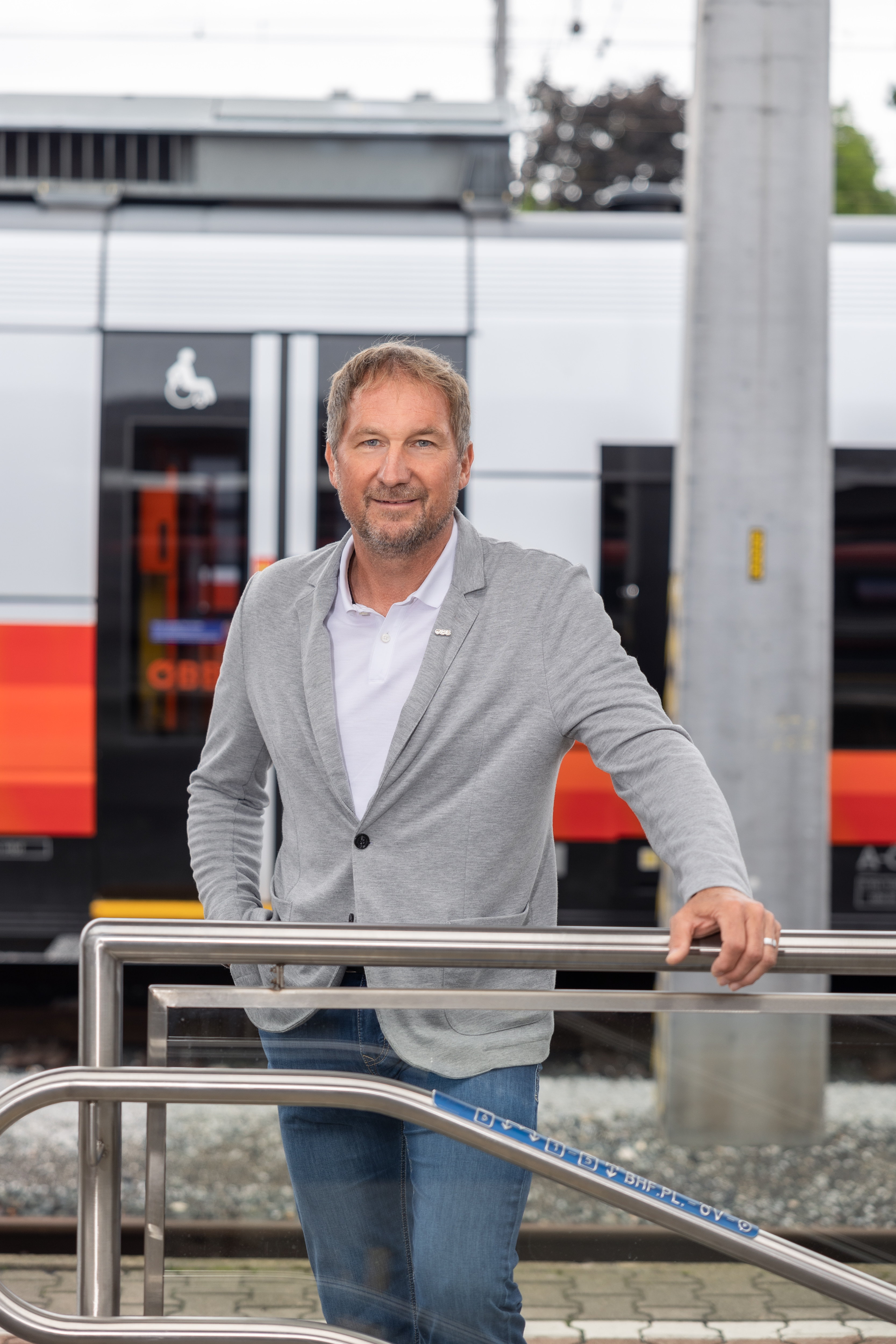 ÖBB Regionalmanager Reinhard Wallner steht auf einem Bahnsteig vor einem Railjet und stützt sich mit einer Hand von einem Stiegengeländer ab