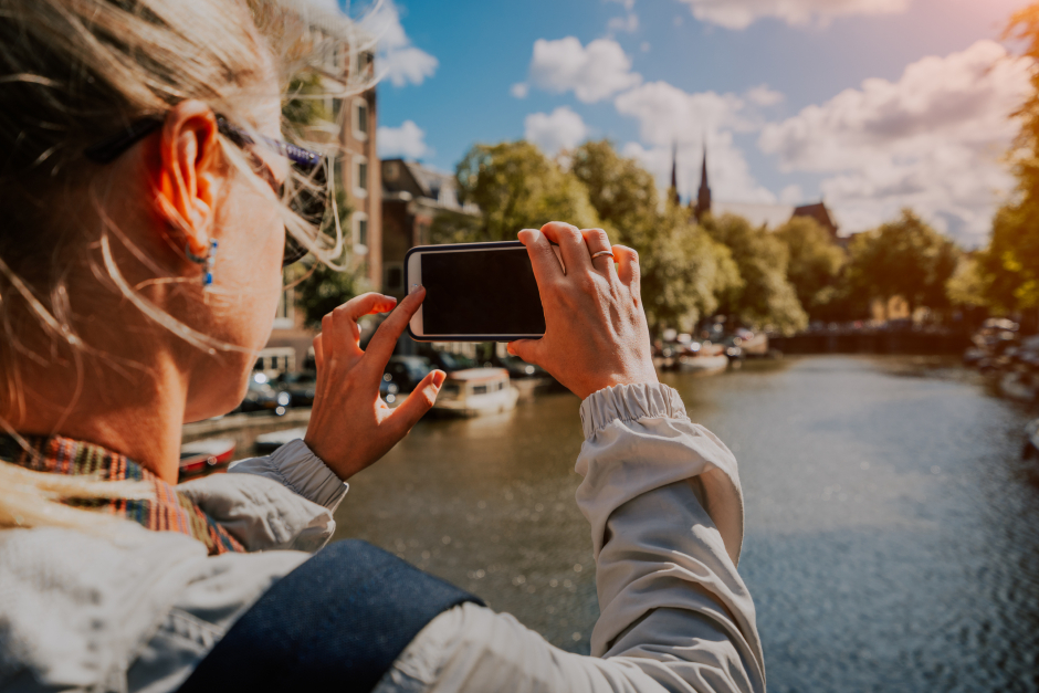 Eine Touristin fotografiert Amsterdams Flußlandschaft | Credit: iStock.com/miniloc