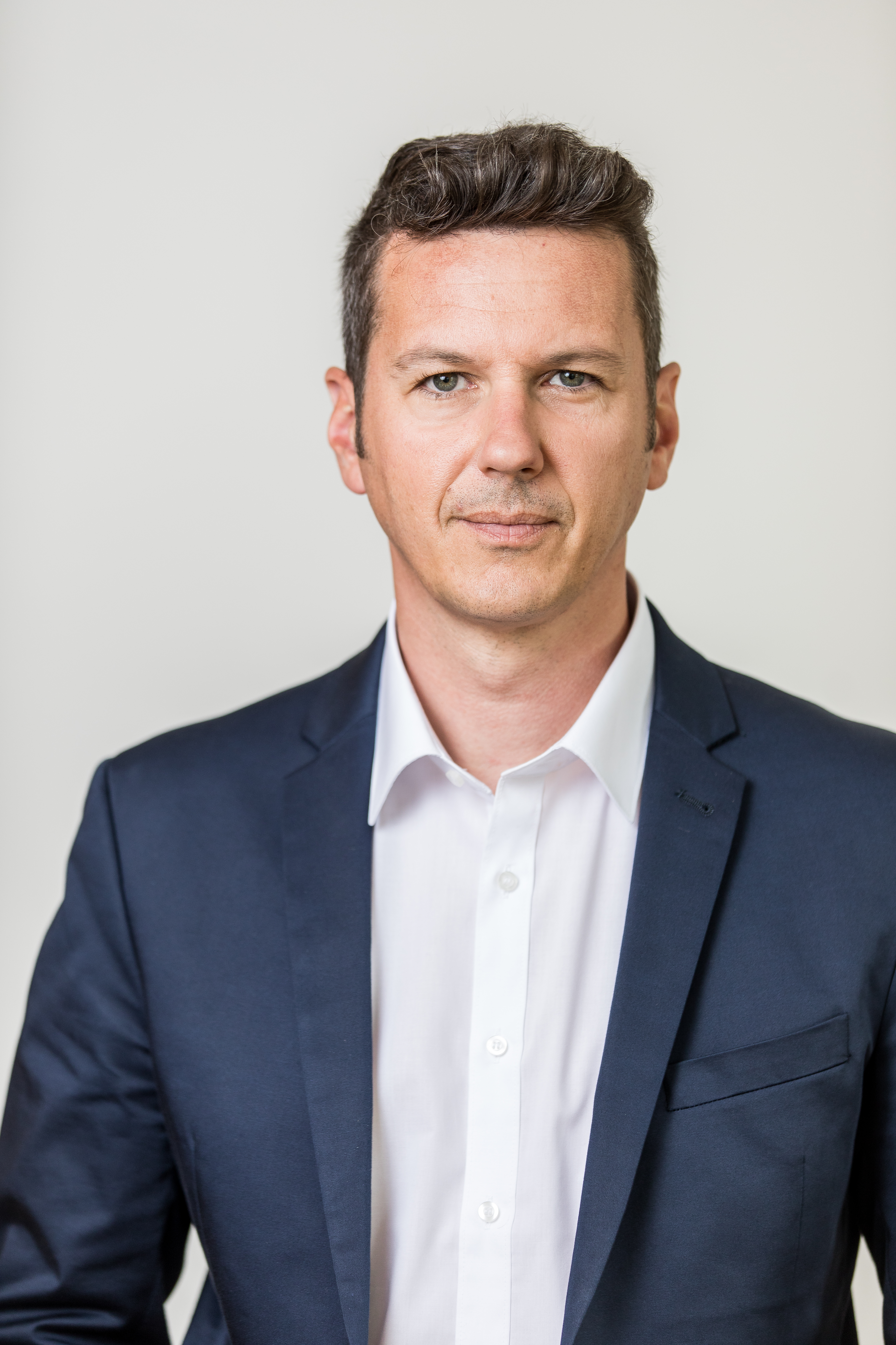 Porträt des Kärntner Landesrats Daniel Fellner, der ein offenes Sakko über einem weißen Hemd trägt