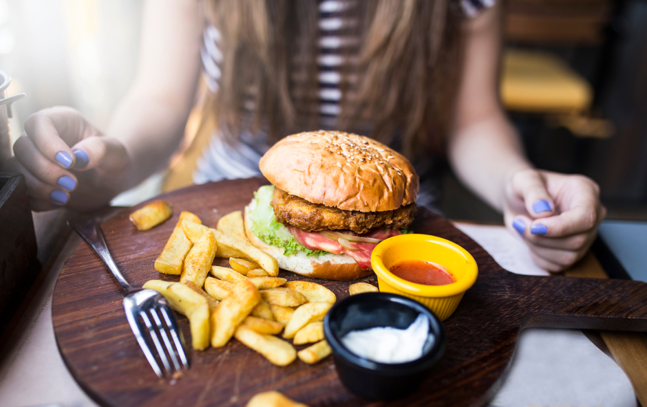 Mädchen sitzt vor Burger und Pommes | Credit: iStock.com/nezarettin azmanoğlu