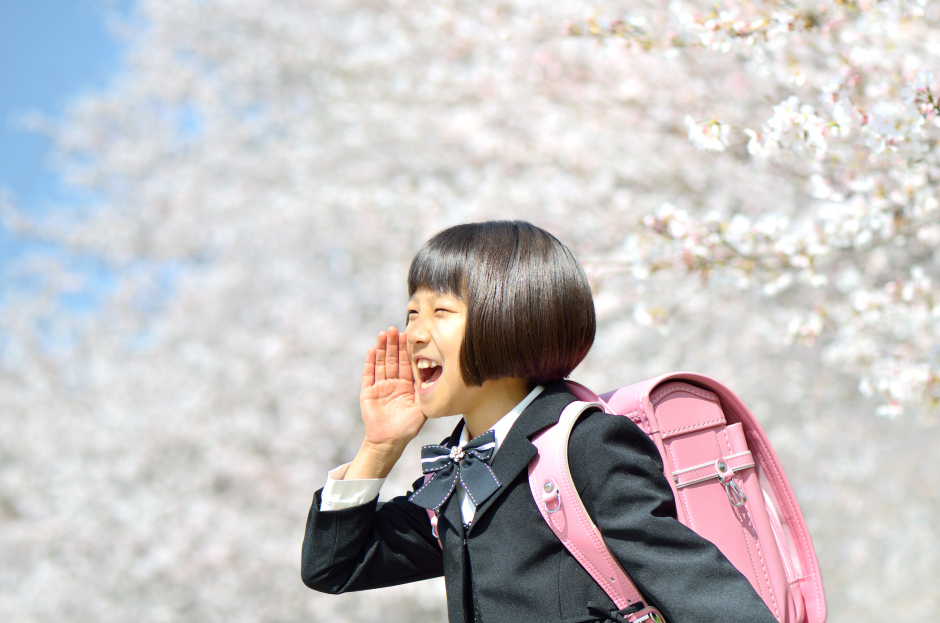 Japanisches Schulmädchen vor einem blühenden Kirschblütenbaum | Credit: iStock.com/hanapon1002