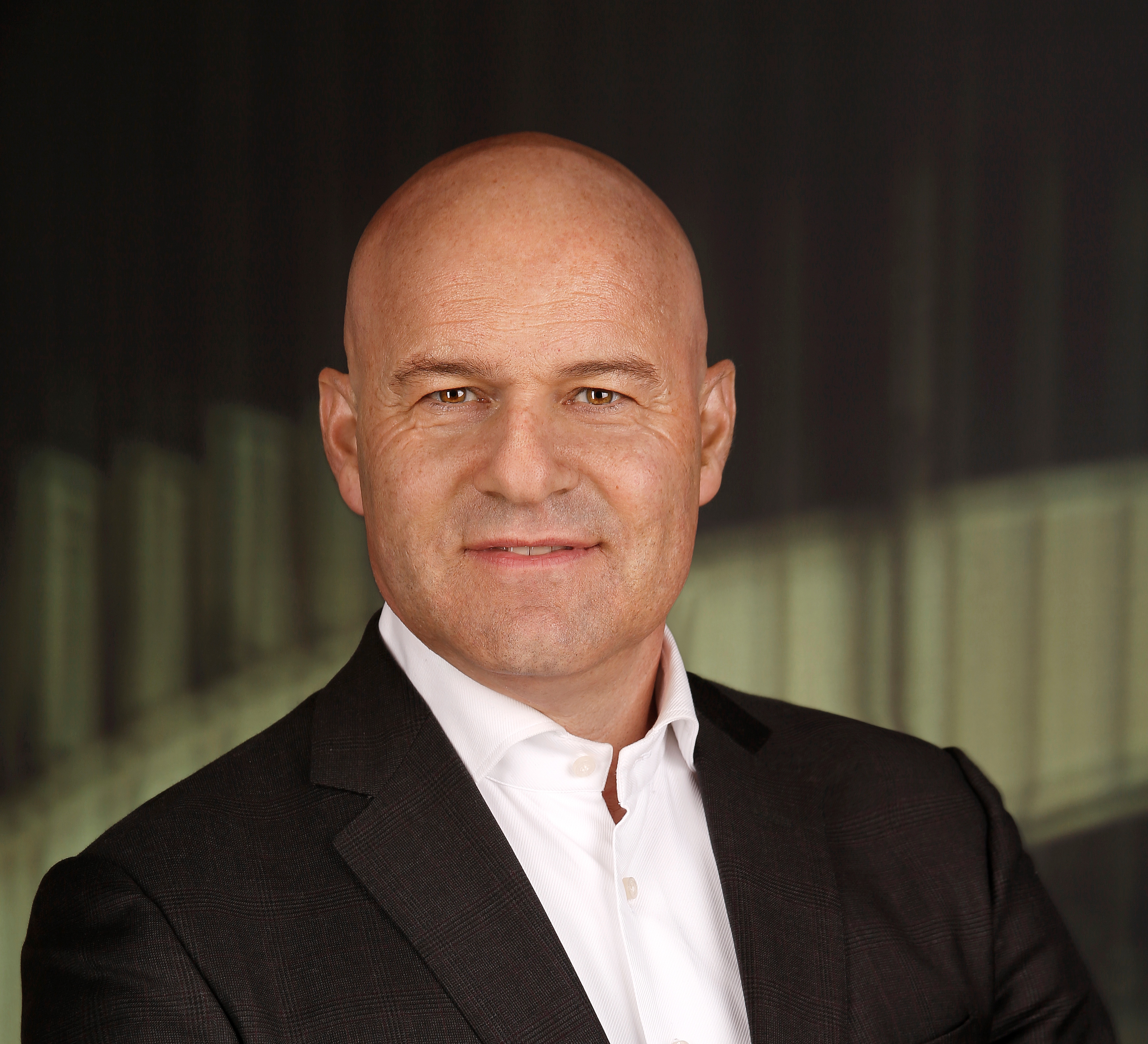 Rechtsanwalt Alexander Todor-Kostic, der mit einem schwarzen Sakko über einem weißen Hemd vor einer Wendeltreppe steht