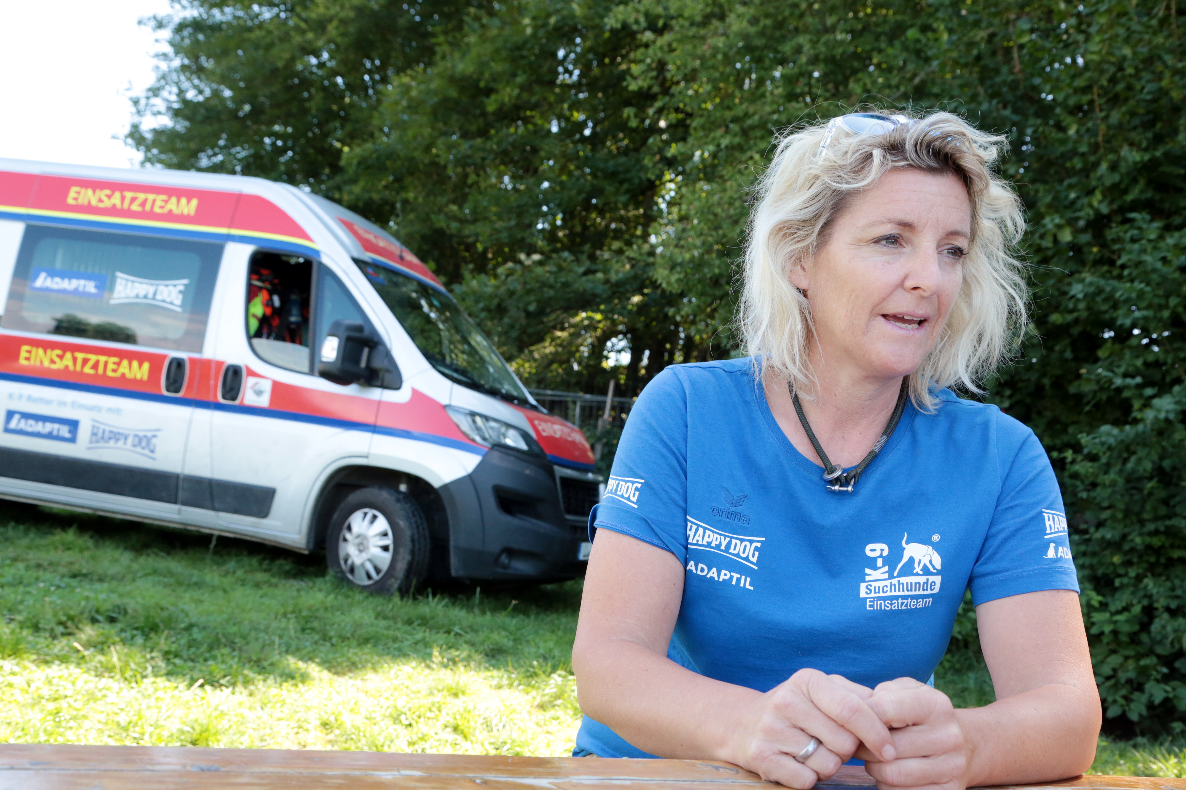 Alexandra Grunow sitzt auf einer Bank vor dem Einsatzwagen des K9 Pro Vermisstensuchevereins