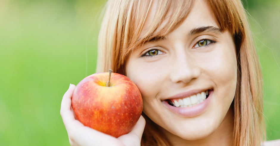 Lächelnde Frau hält einen Apfel| Credit: iStock.com/-101PHOTO-