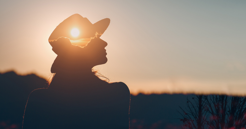 Frau mit Hut genießt den Sonnenuntergang | Credit: iStock.com/primipil