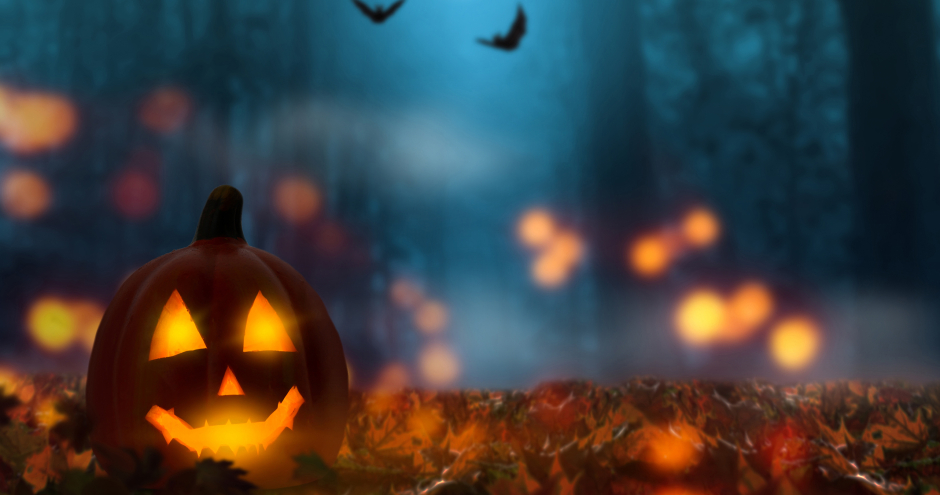 Halloween-Nacht im Wald mit einem geschnitzten, von innen beleuchtenden Kürbiskopf | Credit: iStock.com/winyuu