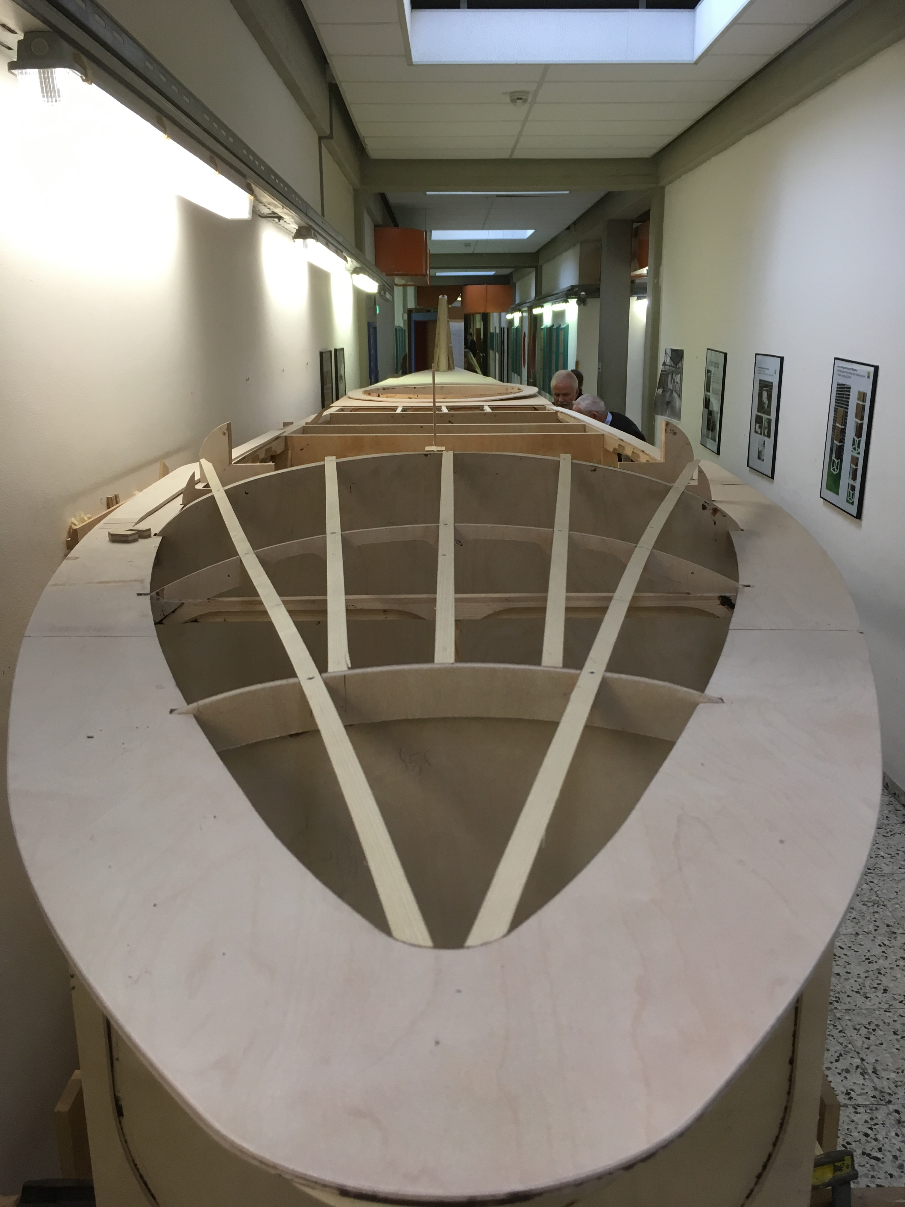 Nahaufnahme des hölzernen Rumpfs der R1-Rekonstruktion im Flur eines Schulgebäudes