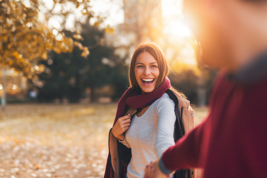 Glückliche Frau Hand in Hand mit einem Mann vor herbstlicher Kulisse | Credit: iStock.com/Jelena Danilovic