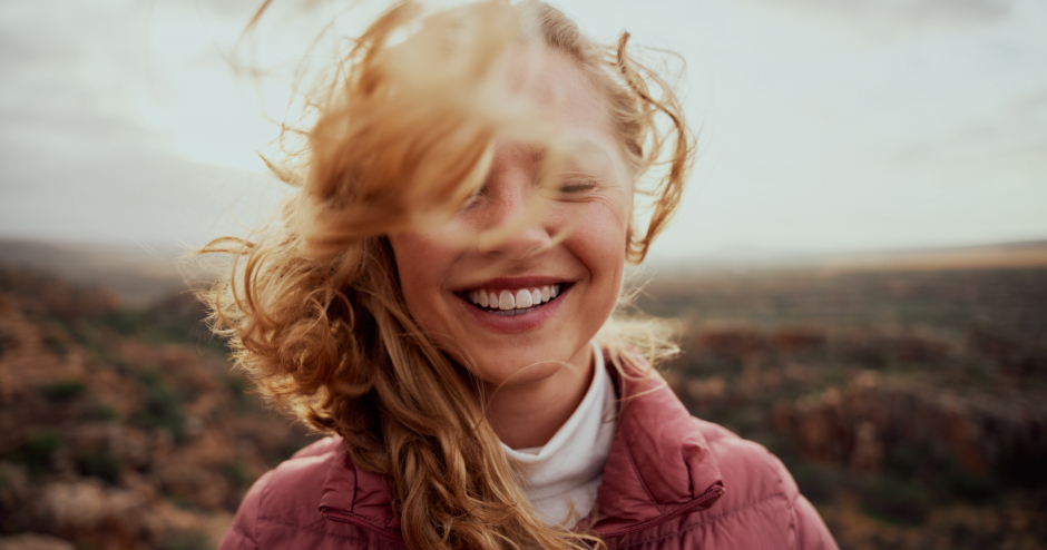 Stürmischer Wind fährt einer glücklichen jungen, rothaarigen Frau durchs lange Haar | Credit: iStock.com/Lyndon Stratford