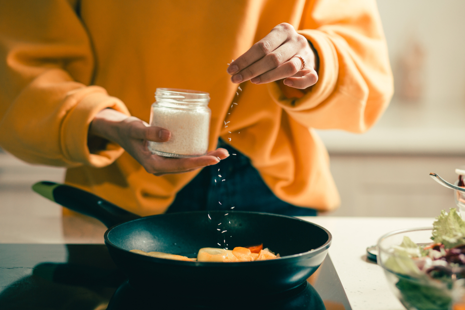Frau würzt ihr Gericht in der Pfanne | Credit: iStock.com/Andrey Shevchuk