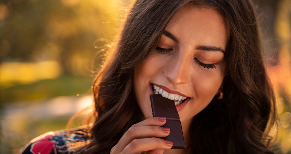Frau isst genüsslich eine Rippe dunkle Schokolade | Credit: iStock.com/Phoenixns