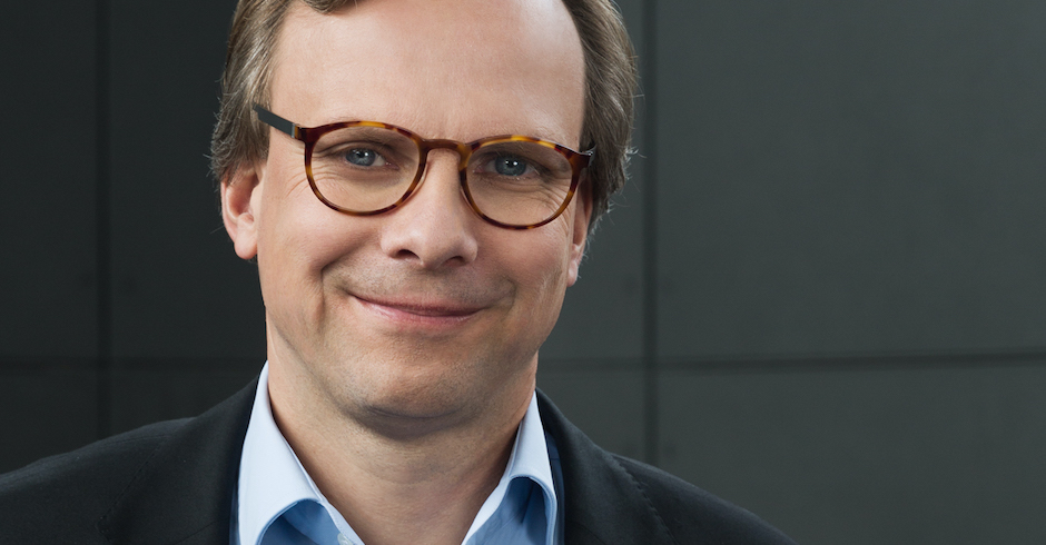 Der Konzernchef vor dunklem Hintergrund, trägt Jackett