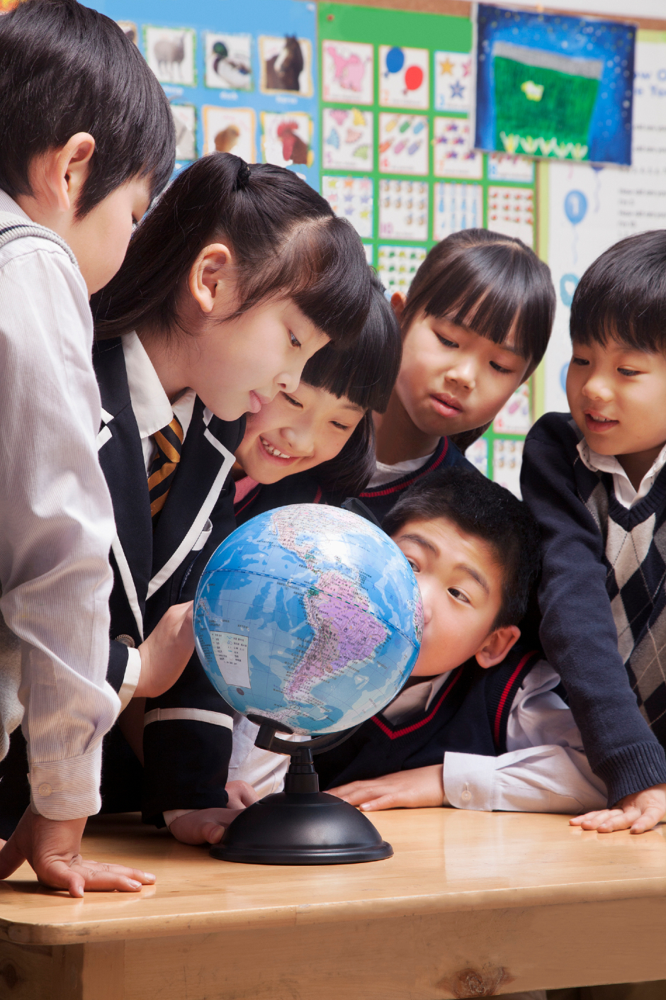 Gruppe chinesischer Schulkinder versammelt sich um einen Globus | Credit: iStock.com/XiXinXing