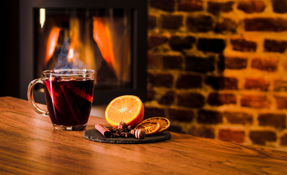 Punsch mit einem Potpourri aus Orangen und Zimtstangen vor einem offenen Kamin | Credit: iStock.com/GPixs