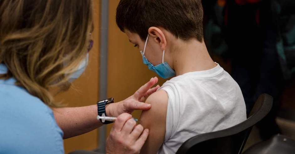 Eine Frau impft einen etwa 8-jährigen Jungen
