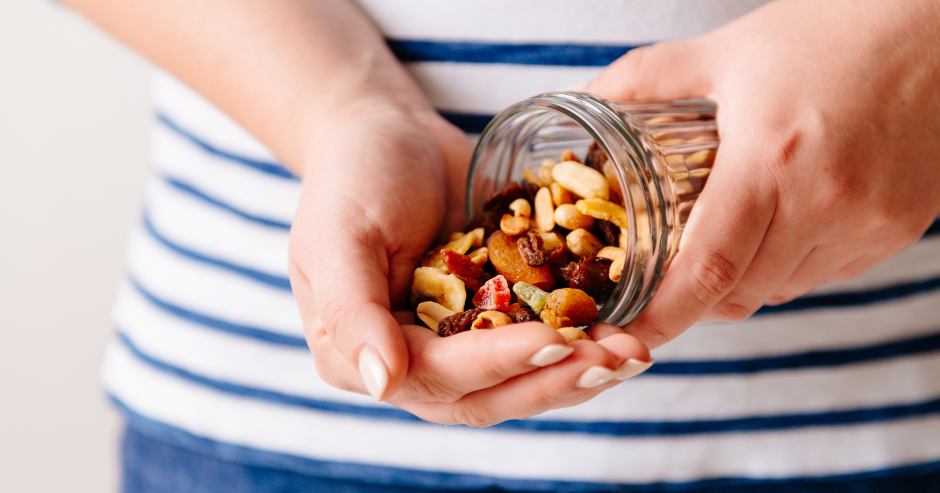 Eine junge Frau portioniert Nüsse in ihrer Hand | Credit: iStock.com/Vovchyn Taras