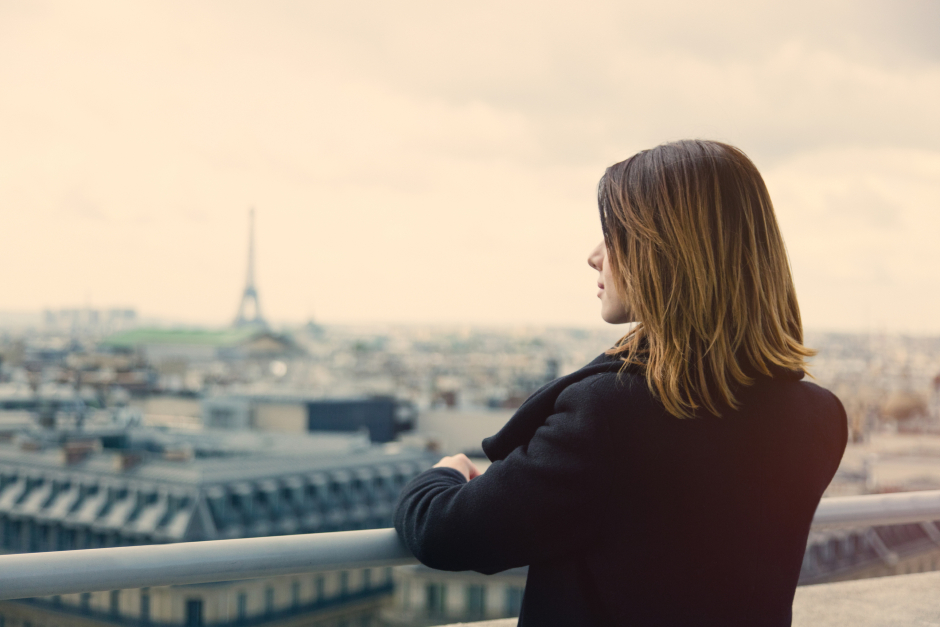 Eine junge Frau genießt von oben das Panorama der Stadt Paris | Credit: iStock.com/Massonstock