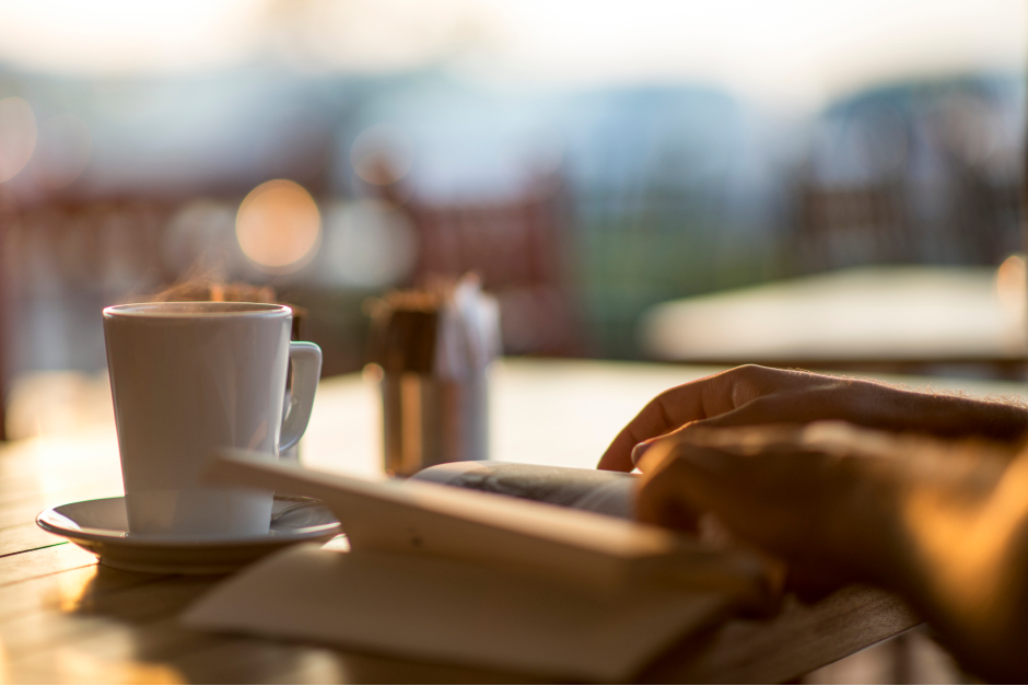 Frau liest ein Buch bei einer Tasse Kaffee | Credit: iStock.com/ilkermetinkursova