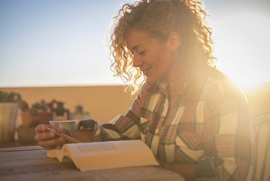 Im Sonnenuntergang liest eine junge Frau ein Buch | Credit: iStock.com/simonapilolla