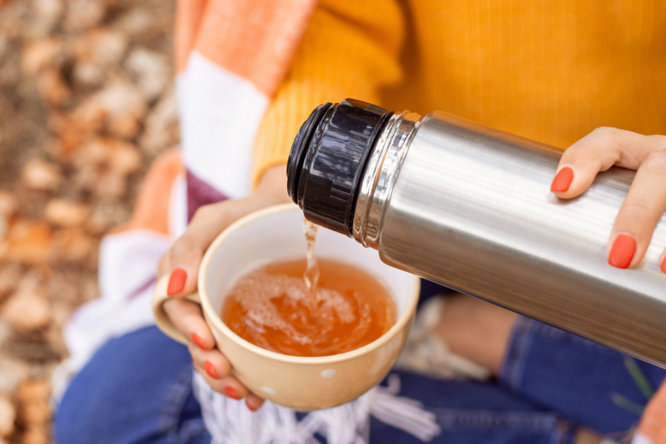 Frau gießt aus einer Thermoskanne Tee in ihre Tasse | Credit: iStock.com/Vitalii Petrushenko