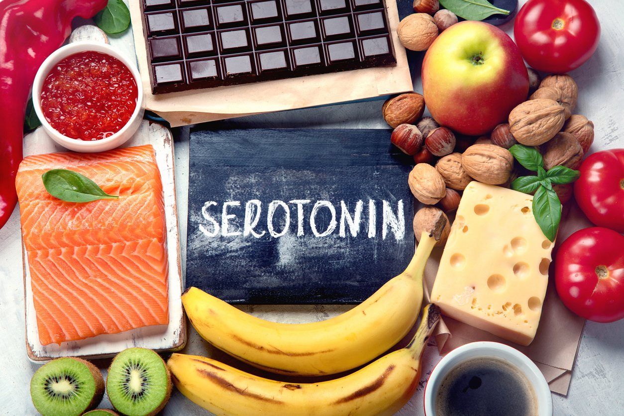 Nahrungsmittel wie Lachs uns Bananen und eine Schiefertafel mit Serotonin Kreideschrift