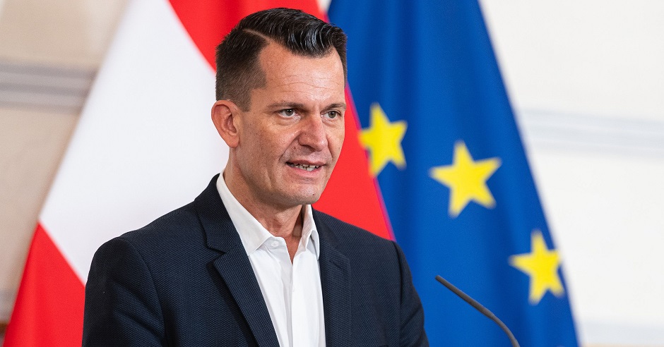 Gesundheitsminister Wolfgang Mückstein bei einer Pressekonferenz vor der Österreichischen und Europäischen Flagge.