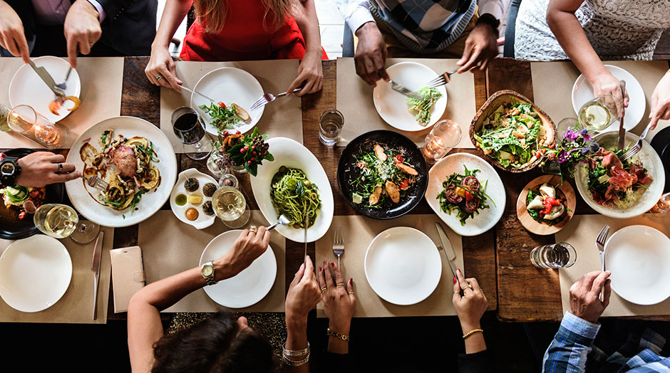 Große Tischrunde beim gemeinsamen Essen | Credit: iStock.com/Rawpixel