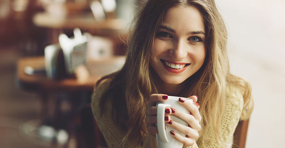 Lächelnde Frau mit einer Tasse Kaffee in der Hand | Credit: iStock.com/ArthurHidden