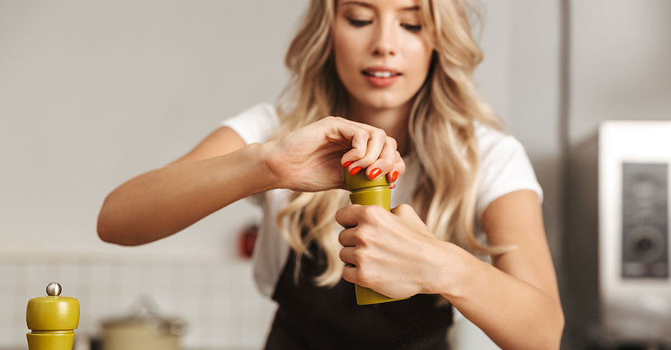 Junge Frau beim Würzen ihrer Speisen | Credit: iStock.com/DeanDrobot