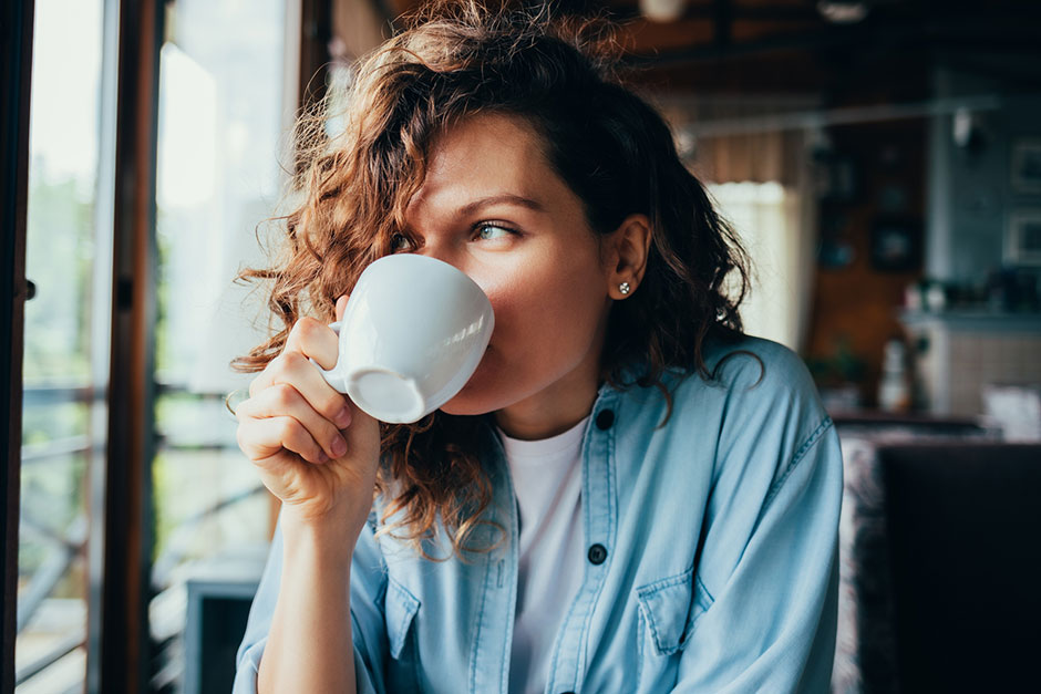 Junge Frau entspannt bei einer Tasse Kaffee | Credit: iStock.com/iprogressman