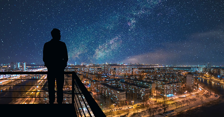 Mann betrachtet vom Balkon aus den nächtlichen Sternenhimmel | Credit: iStock.com/Artem Peretiatko