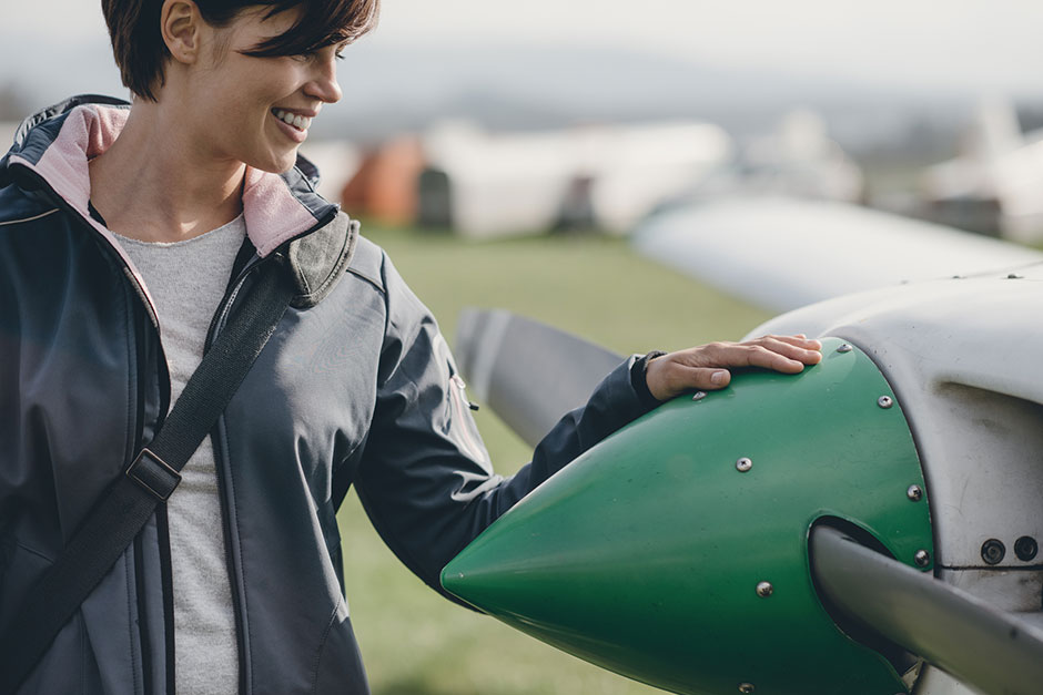 Pilotin legt ihre Hand auf den Propeller ihres Kleinflugzeugs | Credit: iStock.com/cyano66