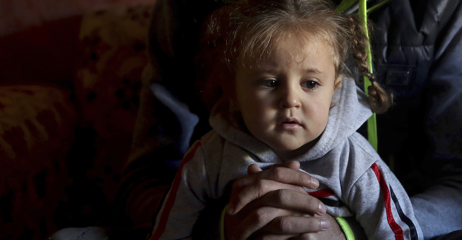 Kleines Mädchen sitzt auf dem Schoß eines Erwachsenen