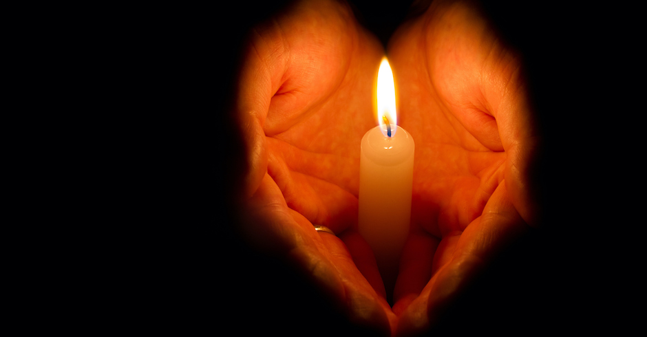 Brennende Kerze wird von zwei Händen geschützt | Credit: iStock.com/Alexey_R