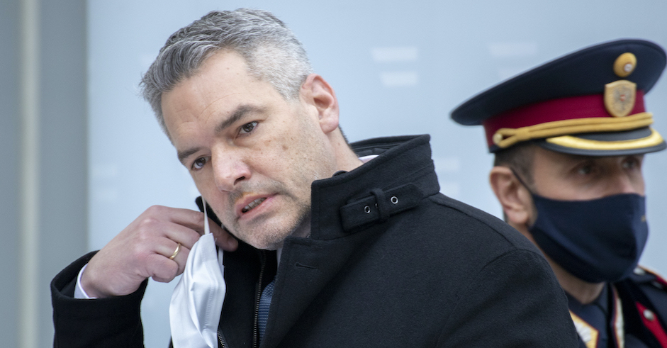 Porträt des Innenministers mit Maske und Polizist im Hintergrund