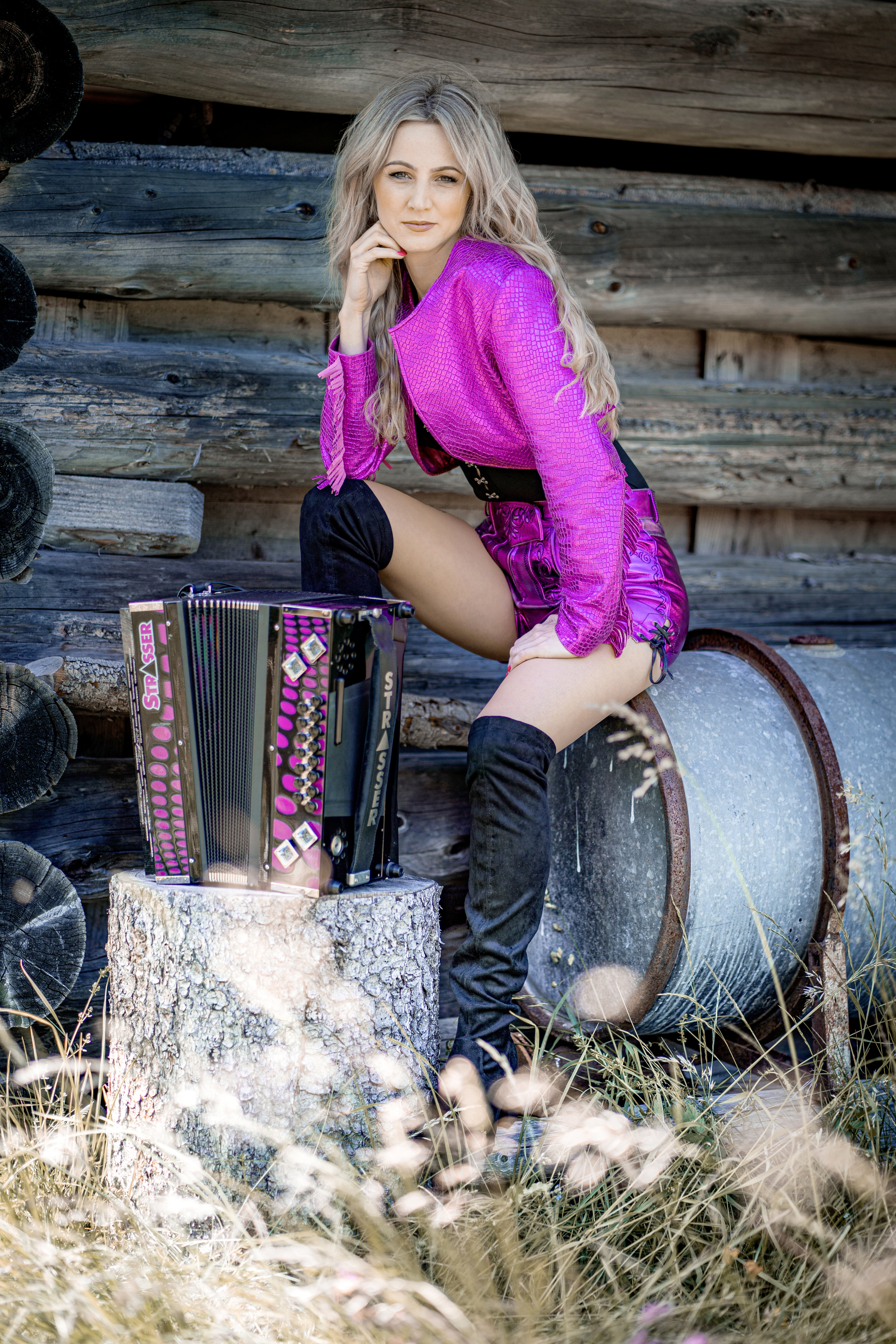 Melissa Naschenweng sitzt auf einem Wassertank vor einer Bergbauernhütte